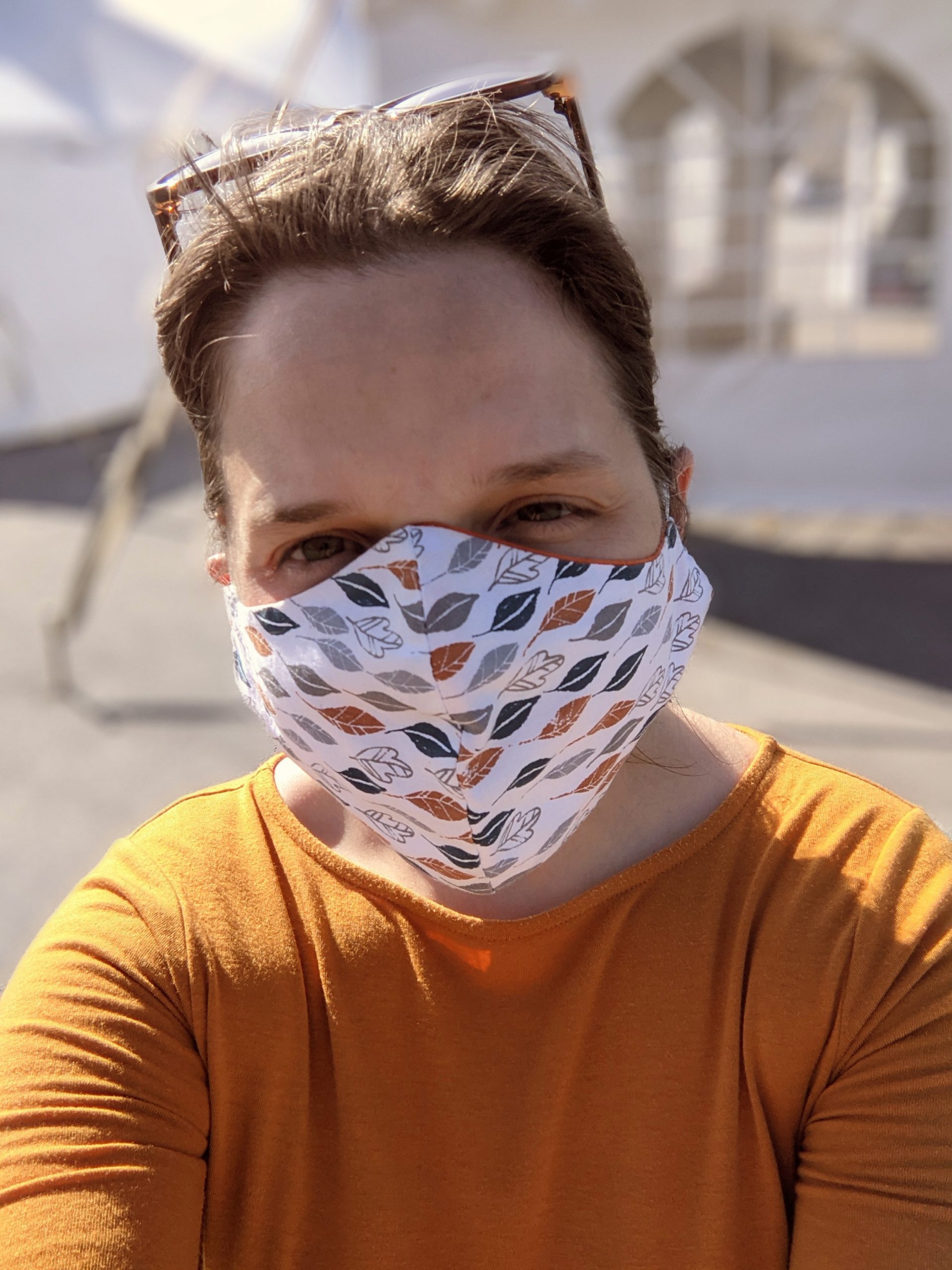 Aili, wearing a mask, standing outside of VDH tents at an outdoor mass vaccination site.