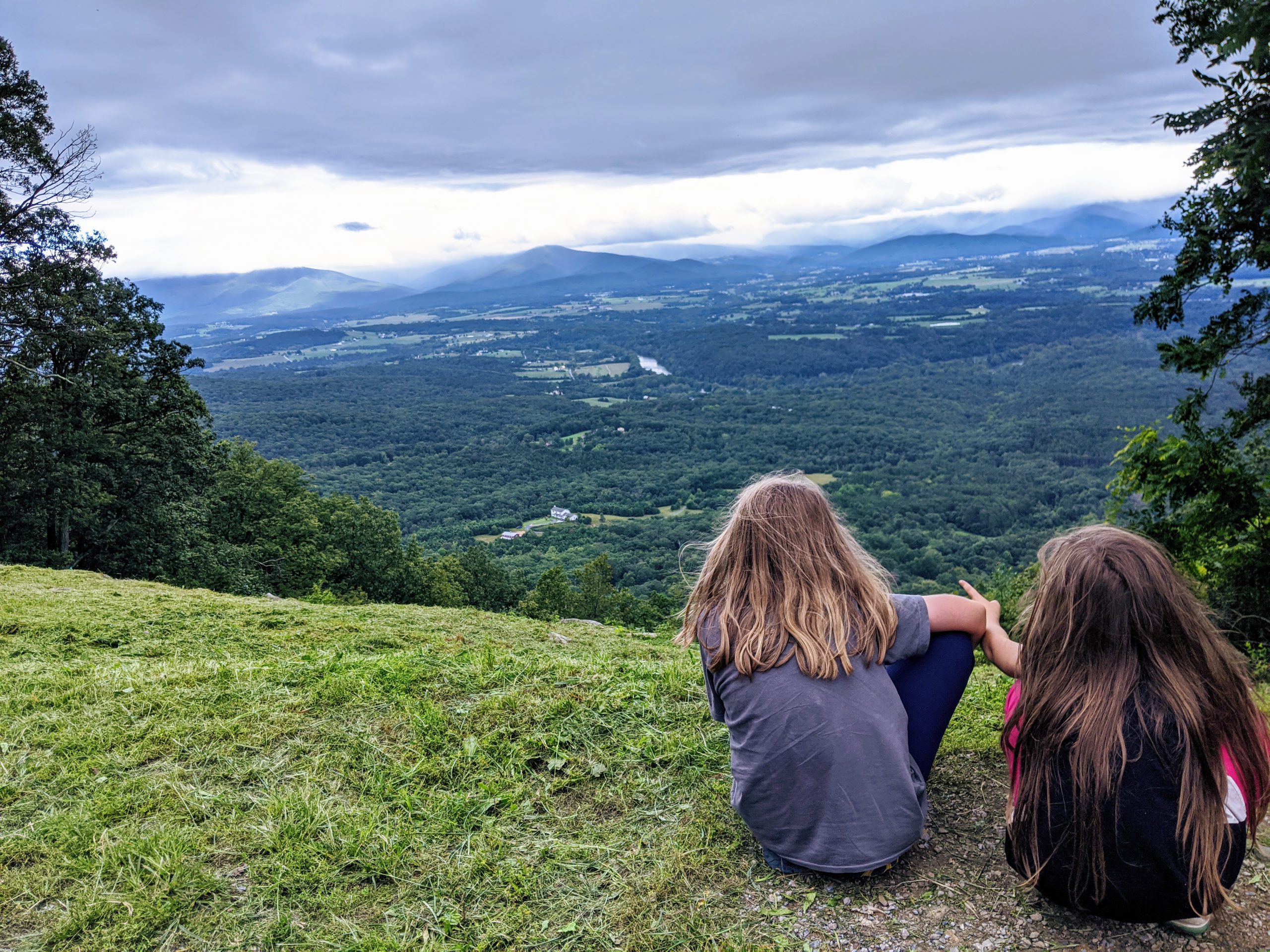Petra and Silas seen from behind, looking down over the Shenandoah Valley from a high vantage point.