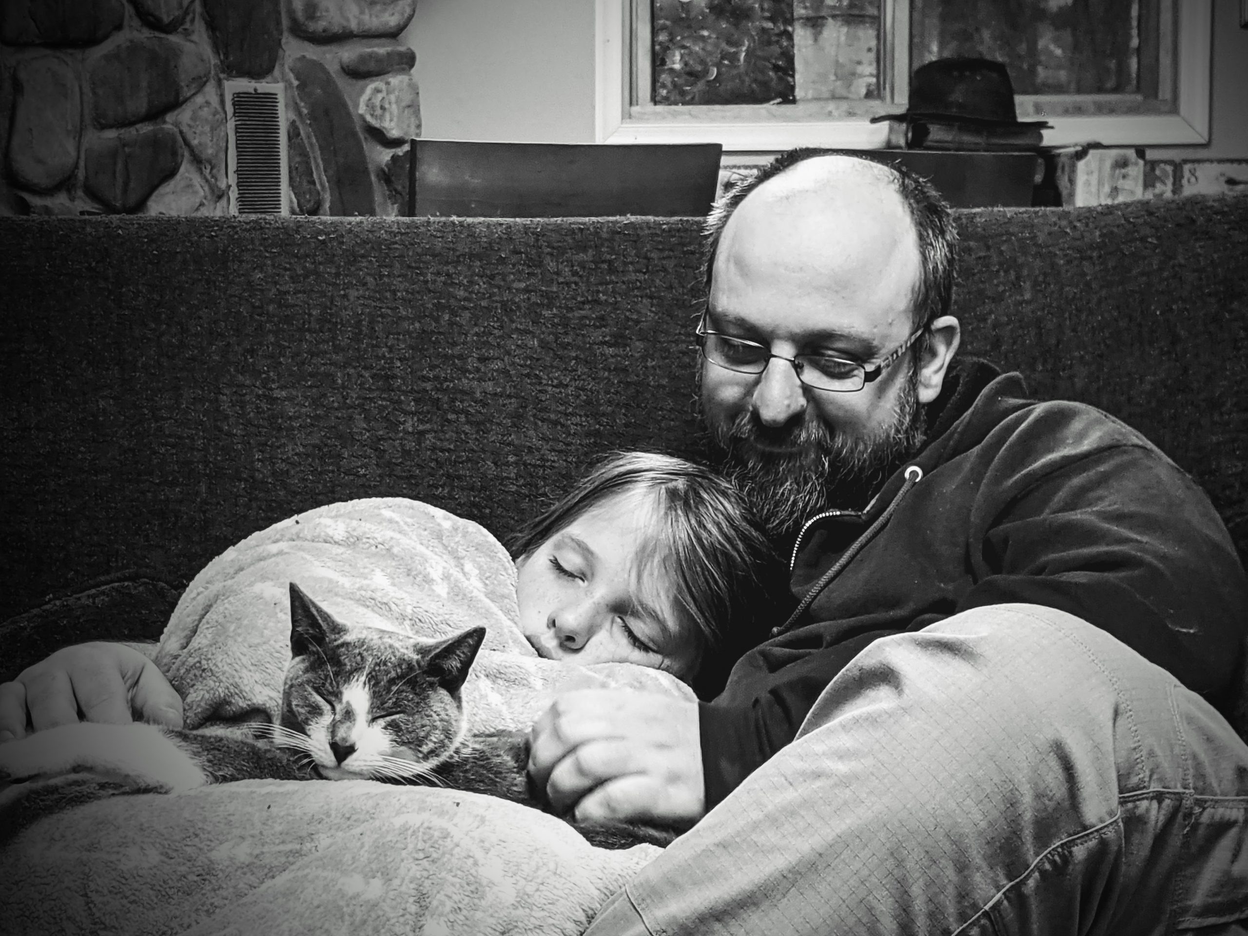Silas cuddling with his dad and cat