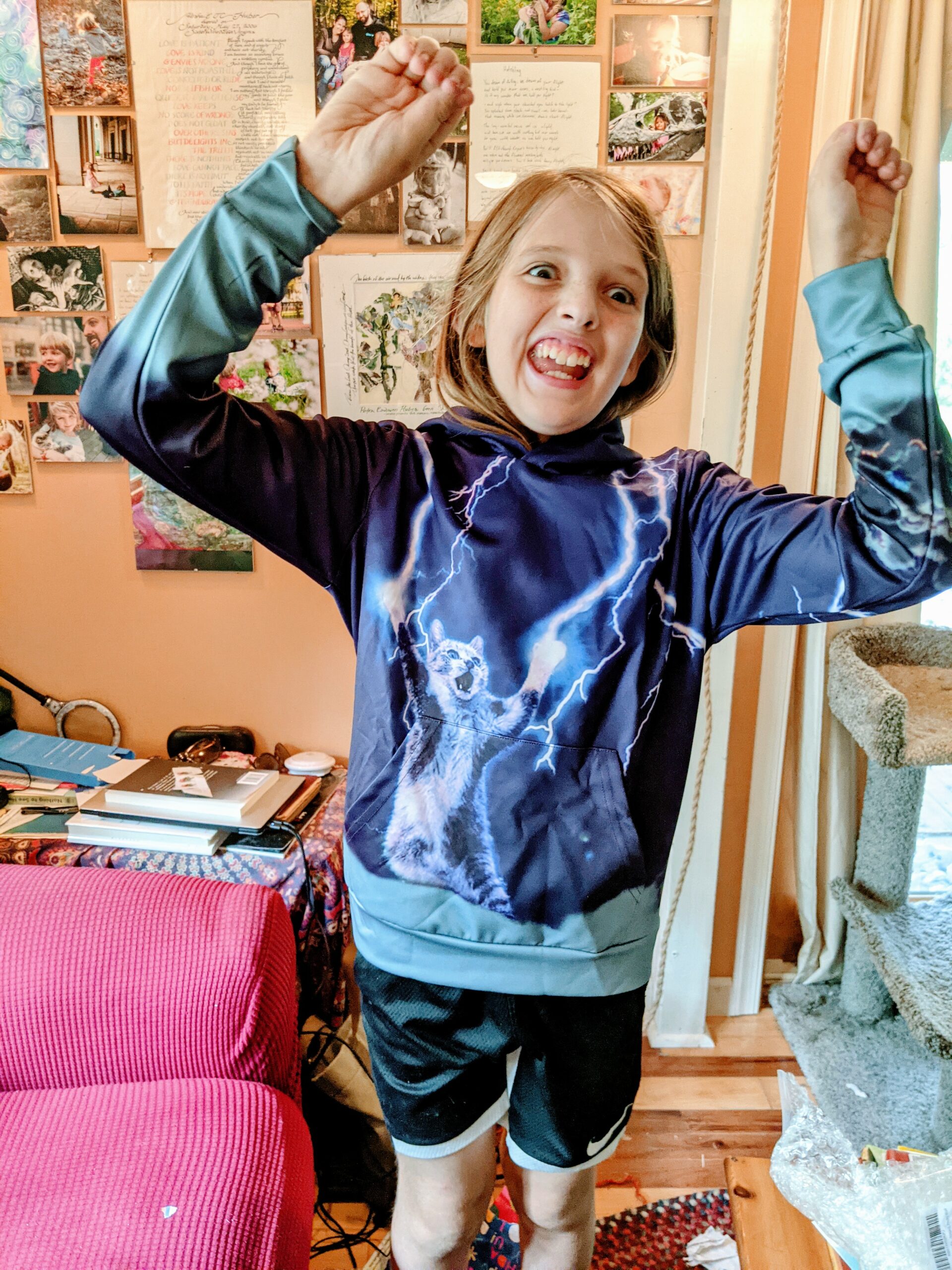 Silas, wearing a shirt with a picture of a cat shooting lightning from its paws, mimicking the gesture.