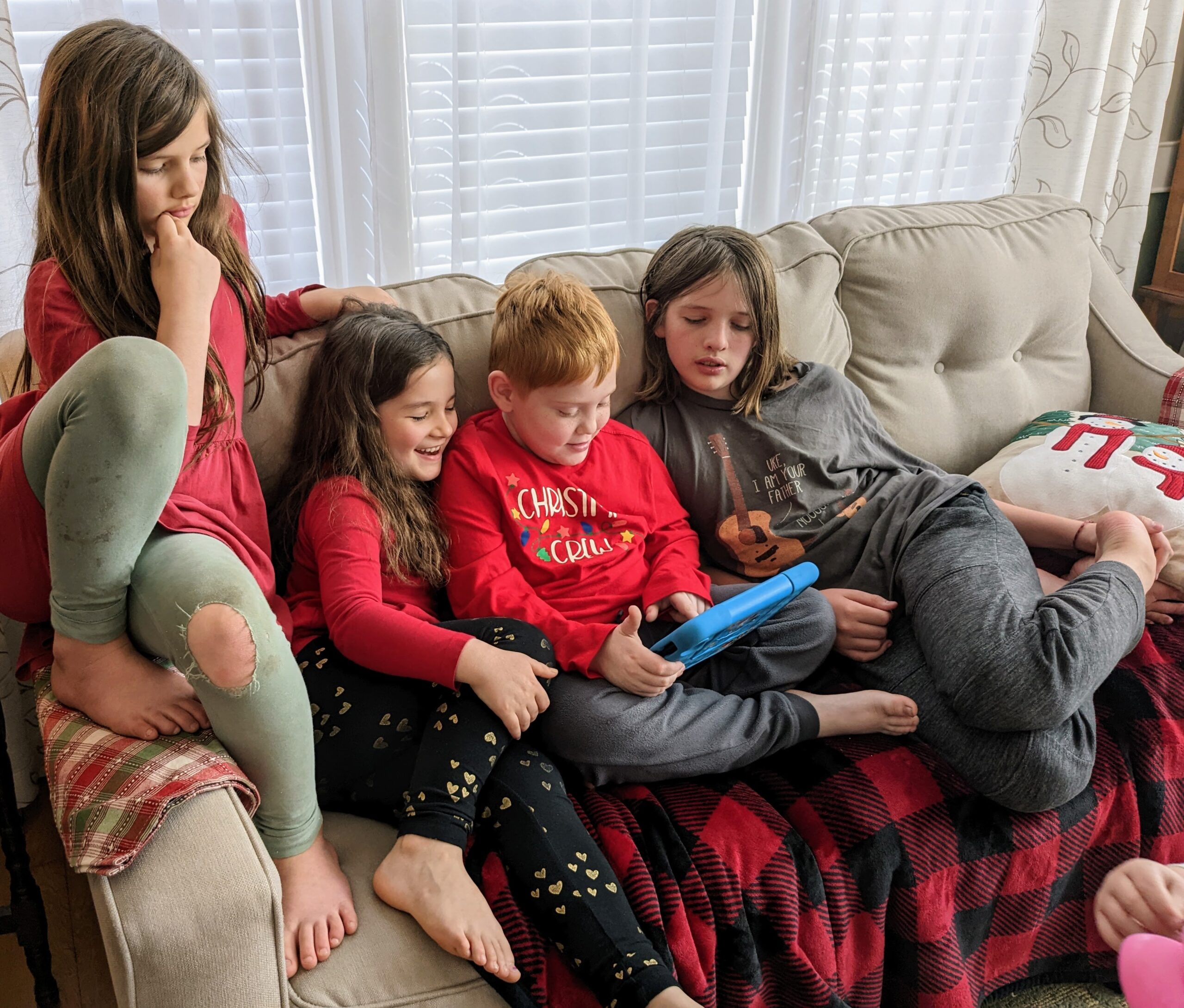 Petra, Elora, JJ, and Silas sitting on the couch, watching some game on JJ's tablet