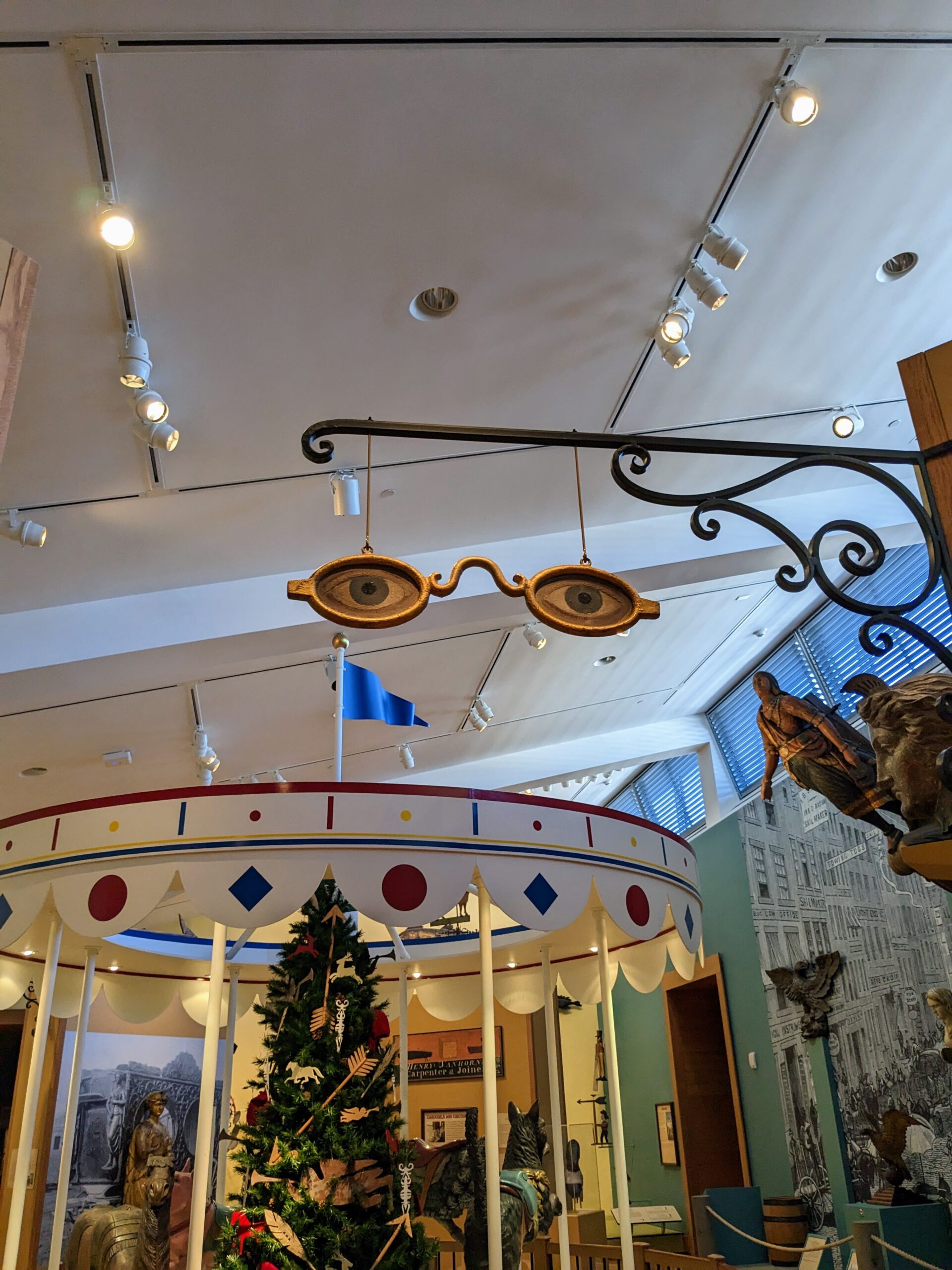 An exhibit with early business signs, featuring a pair of glasses for an optometrist's shop.