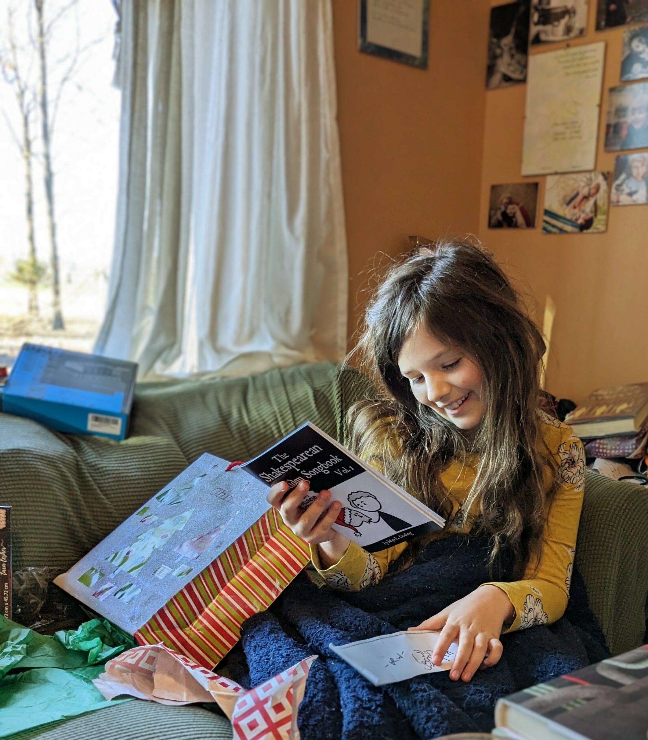 Petra smiling at the Good Tickle Brain Holiday Song Book, which she has just received.